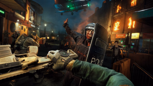 A "No More Room in Hell 2" screenshot showing a chaotic street fight against zombies, with fire, a soldier, and a police zombie in focus.