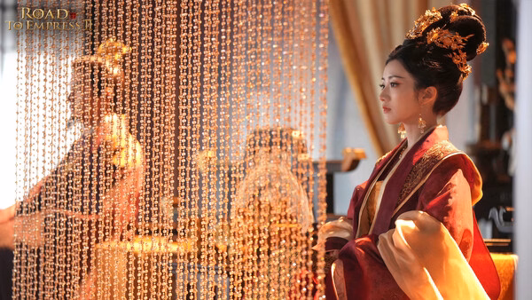 Screenshot from Road to Empress II showing two characters in elaborate royal attire behind golden beaded curtains.